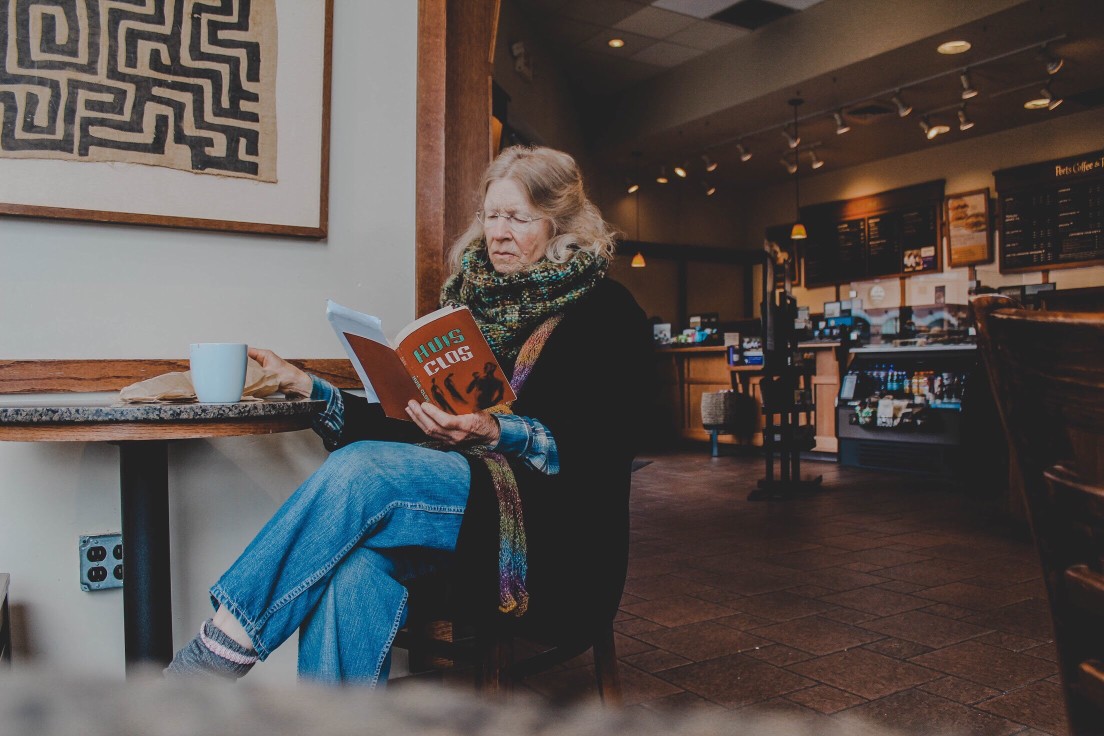 older-woman-reading-and-drinking-coffee-at-cafe