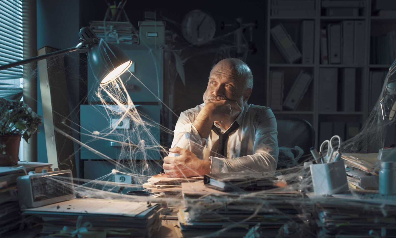 older-man-looking-discouraged-at-desk-with-cobwebs