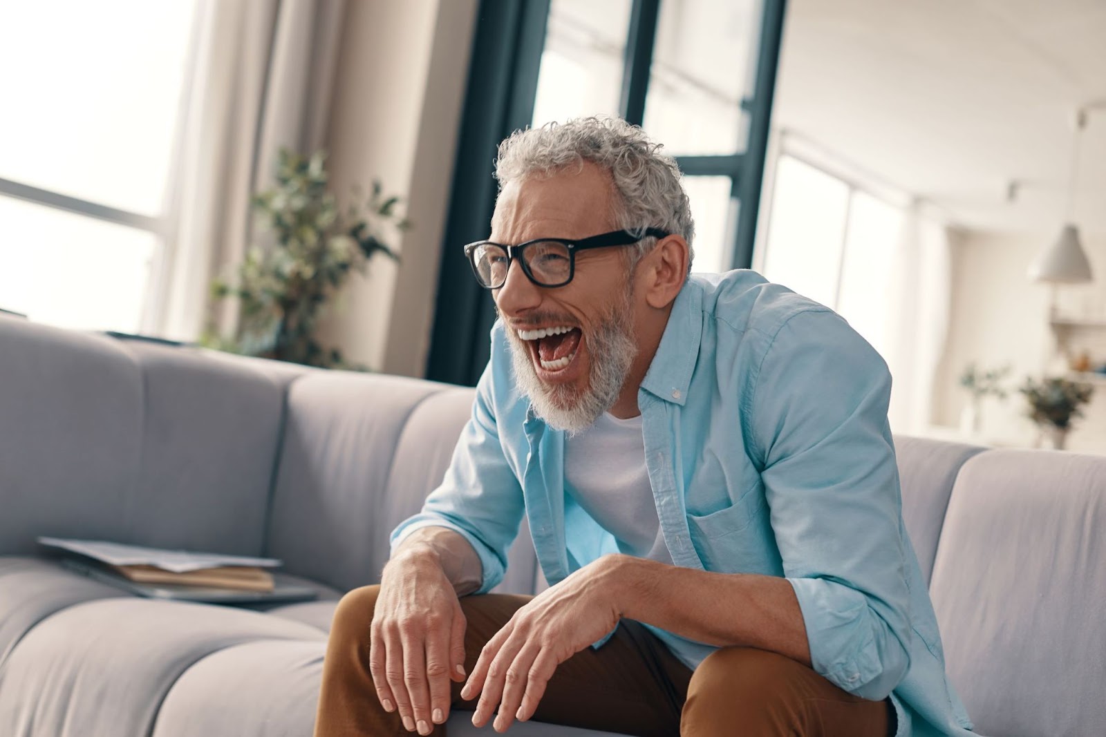 senior-man-sitting-on-couch-laughing