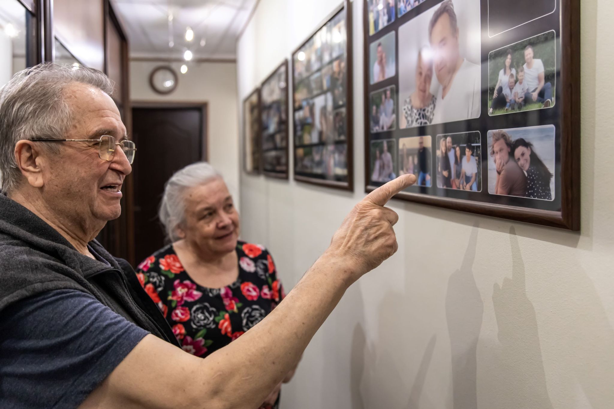 older-couple-looking-at-family-photos-on-wall