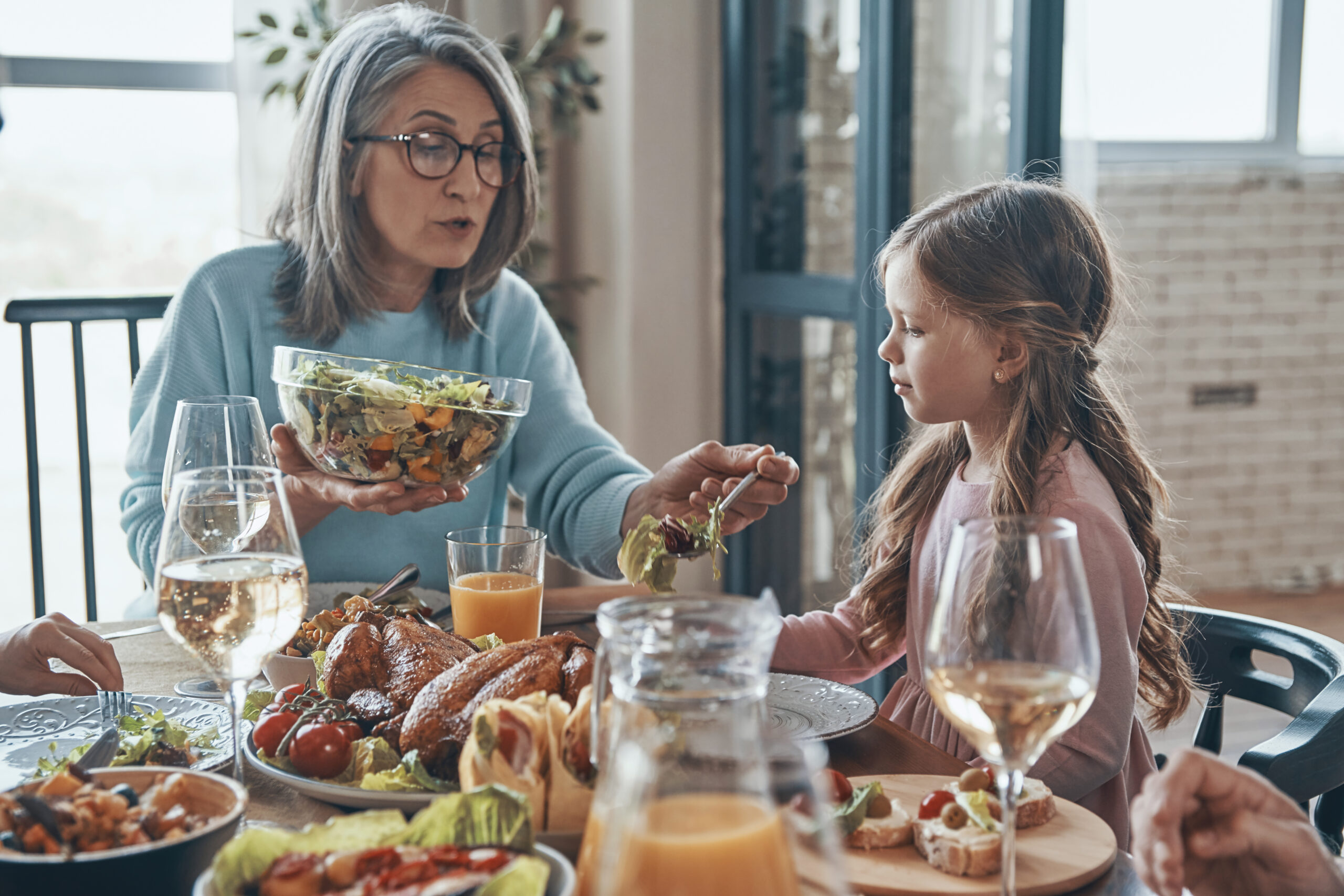 senior-woman-helping-girl-with-her-thanksgiving-plate