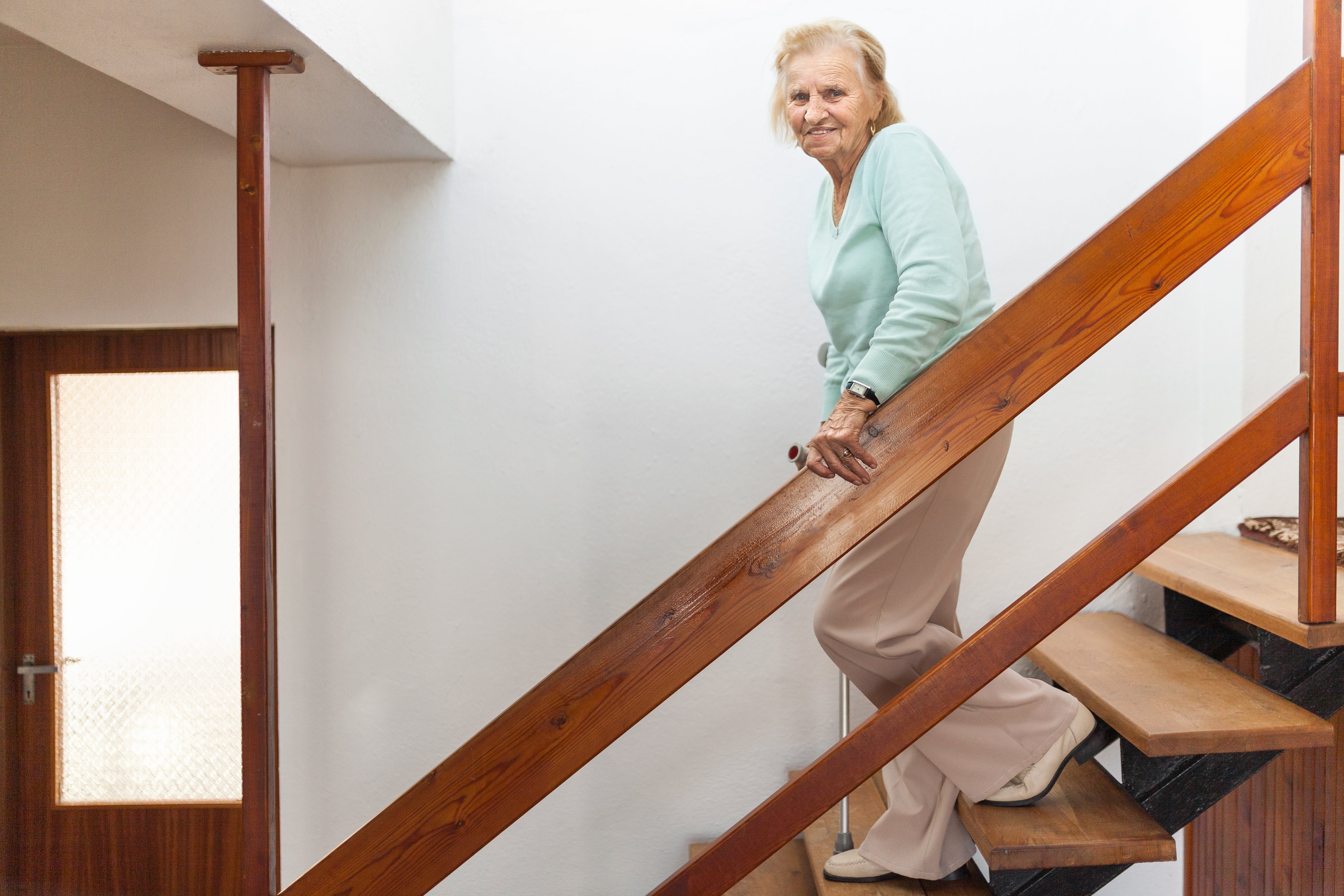 elderly-woman-at-home-using-a-cane-to-get-down-J6R2QPN