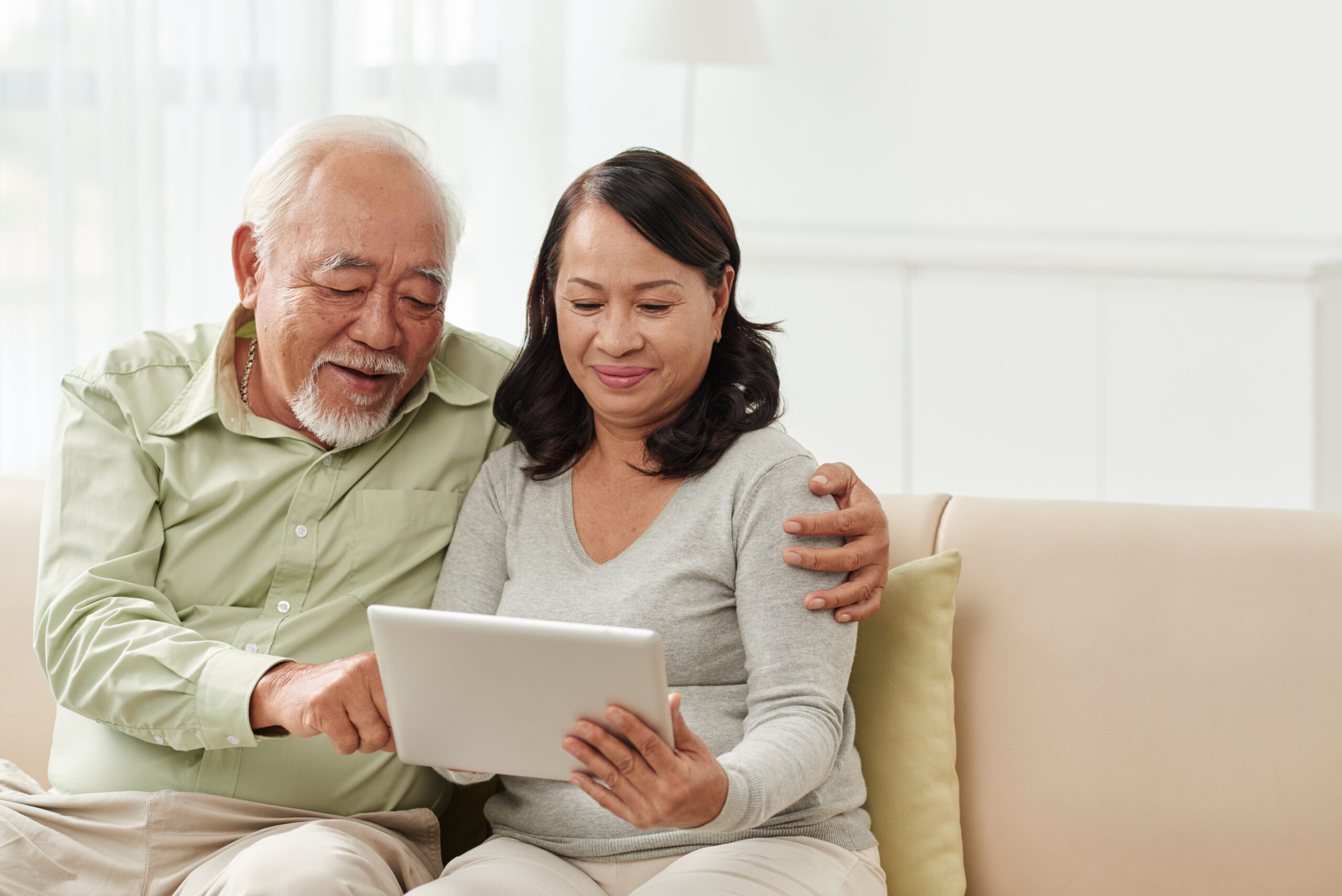 senior-couple-looking-at-tablet-on-couch