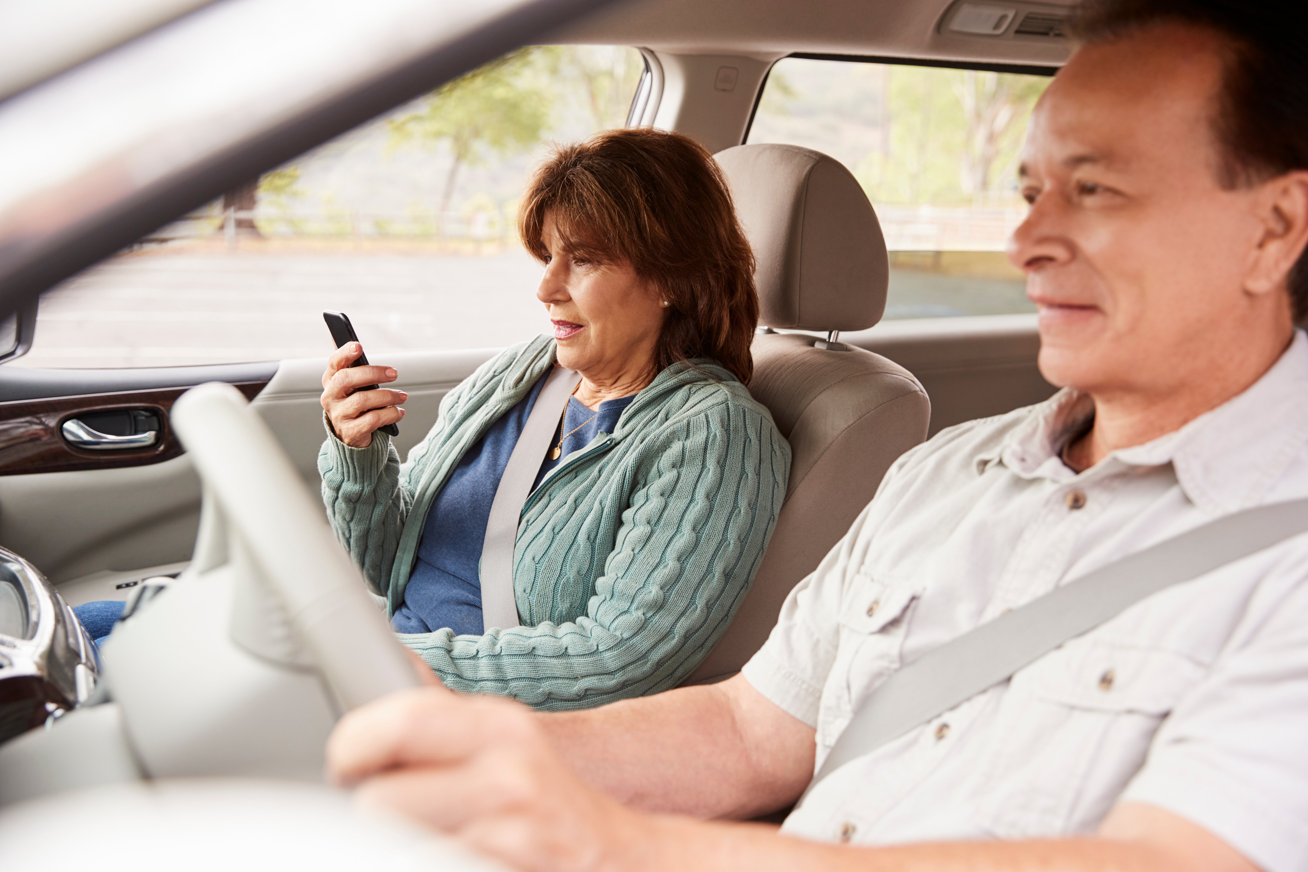 woman-passenger-using-gps-on-smartphone-during-car-9AZDGSY